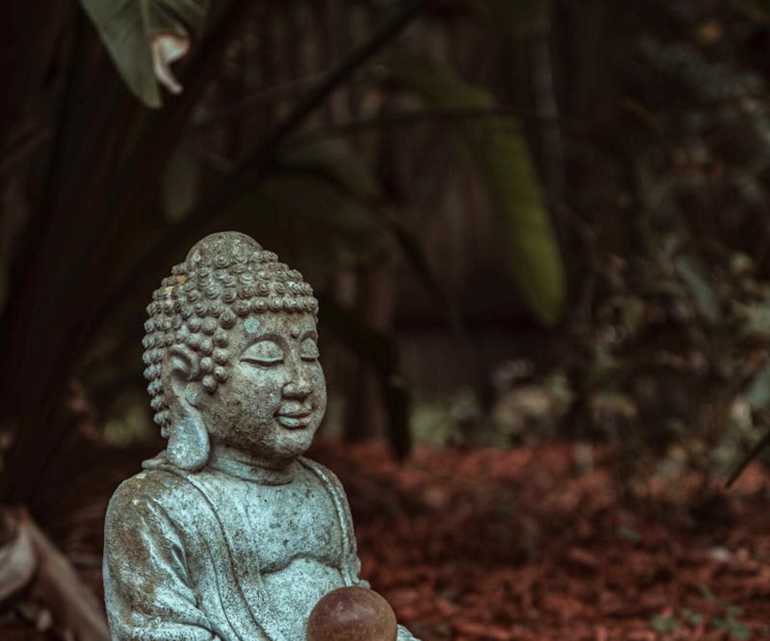 A buddha statue sitting in the middle of the ground