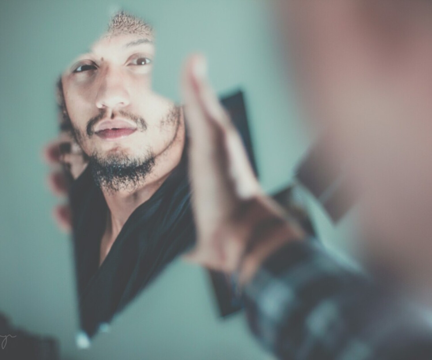 selective focus photography of man's reflection on a broken mirror