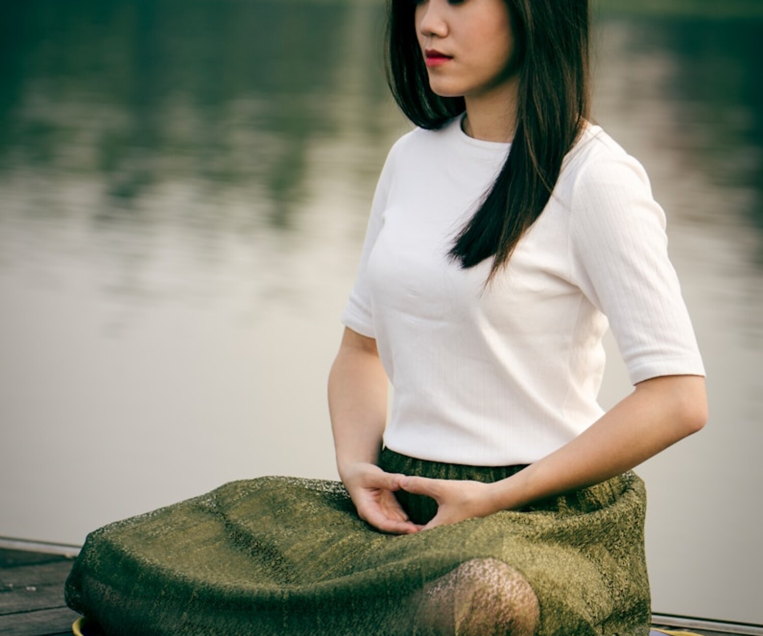 woman meditating on wooden dock during daytime