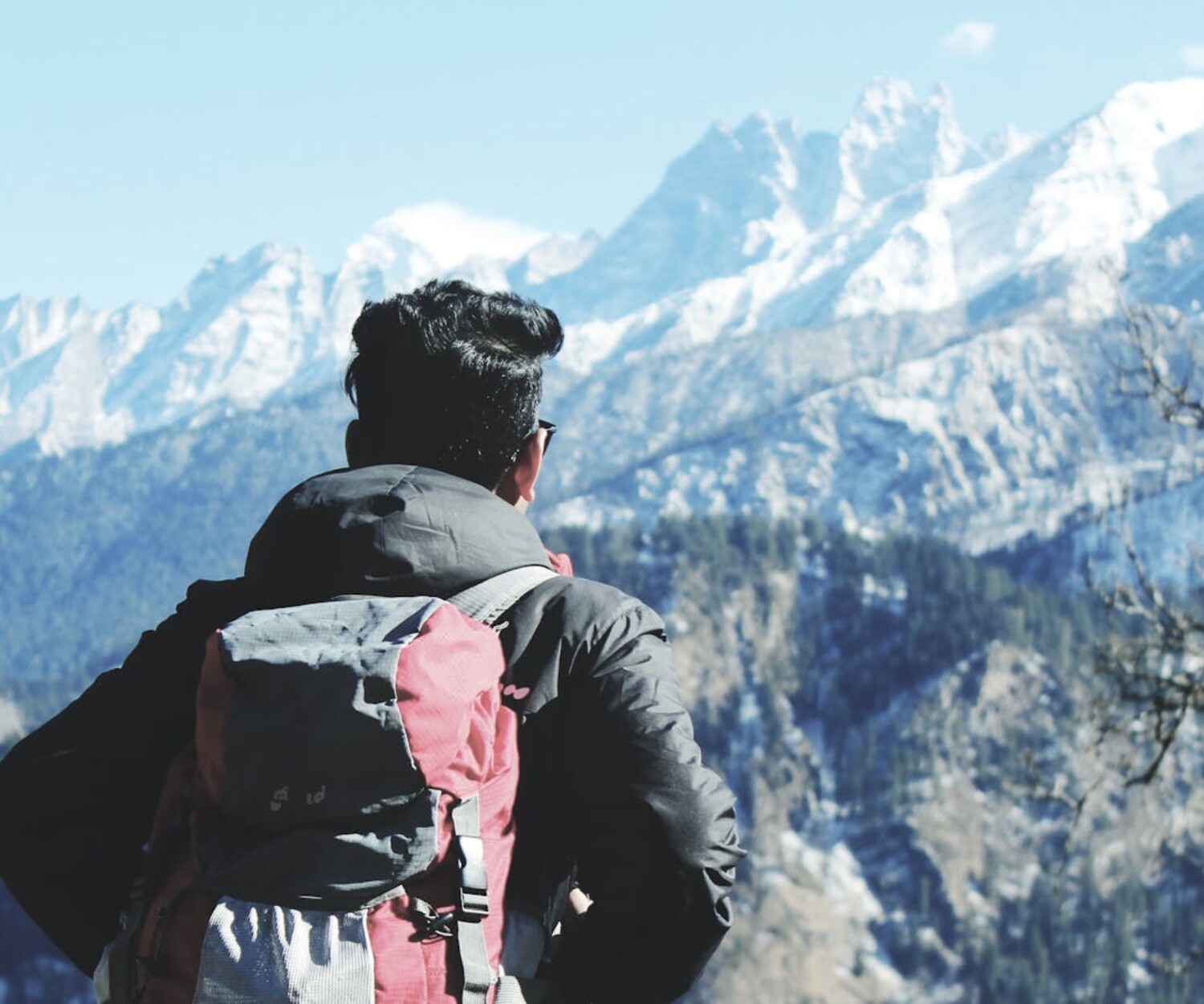 A backpacker admires the snowy peaks in Shimla, India, capturing the essence of adventure and nature.