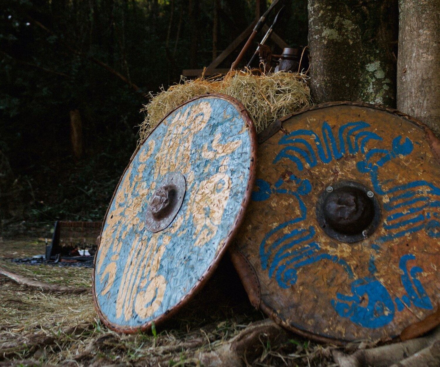 A pile of hay sitting next to a forest filled with trees